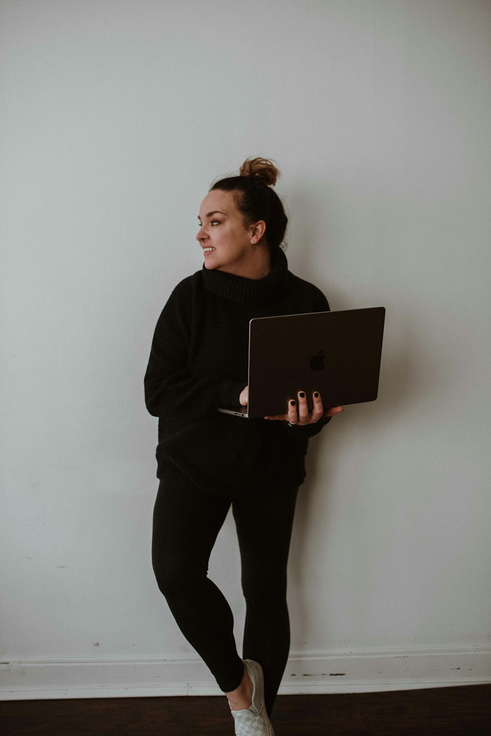 a woman in a black sweater holding a laptop