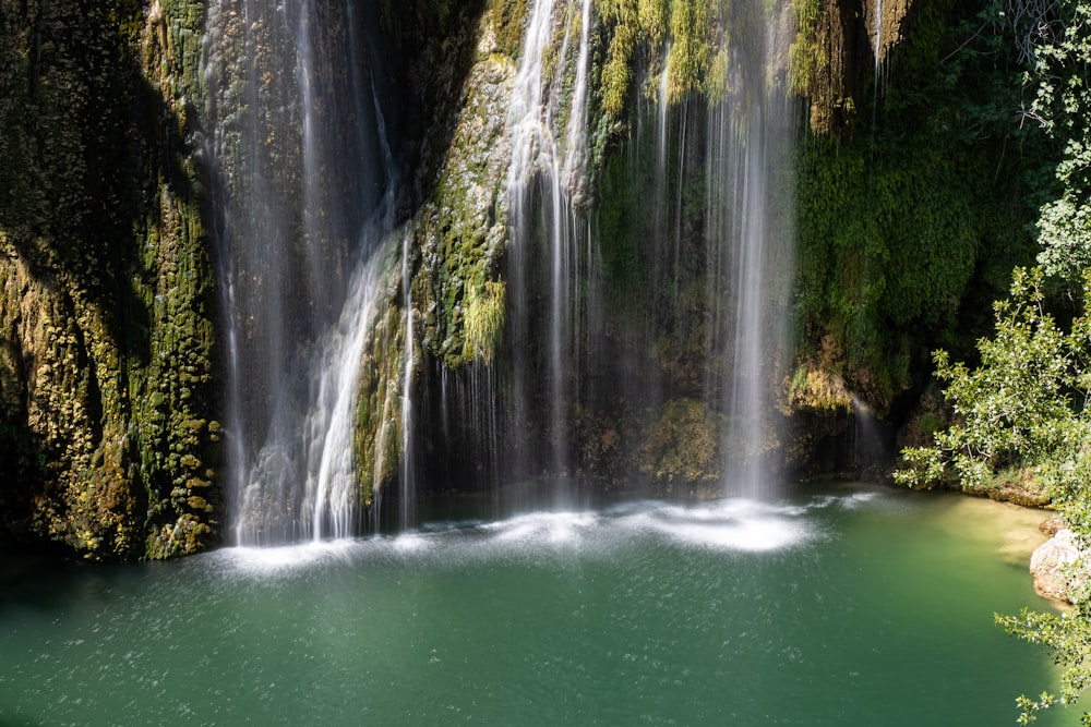 a large waterfall with a body of water in front of it