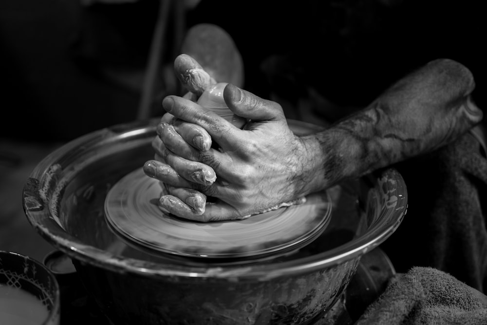 a person holding a potter's hands on a potter's wheel