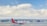 A SpiceJet airplane is positioned on the runway with a large modern terminal building in the background. The sky is mostly clear with a few scattered clouds. The airplane is white with a red tail that features a yellow design.