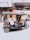 A motorized rickshaw is moving quickly down a street. The blurred background suggests motion and speed. The rickshaw is carrying a person who is bundled up in warm clothing, with decorative cushions on the passenger seats.