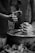 Hands are actively shaping clay on a pottery wheel, demonstrating the art of pottery-making. Two sets of hands are visible, one guiding and the other learning. The scene is intimate and focused, showcasing a transfer of skills.