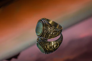 Elegant silver ring with intricate floral engravings displayed on a marble surface.