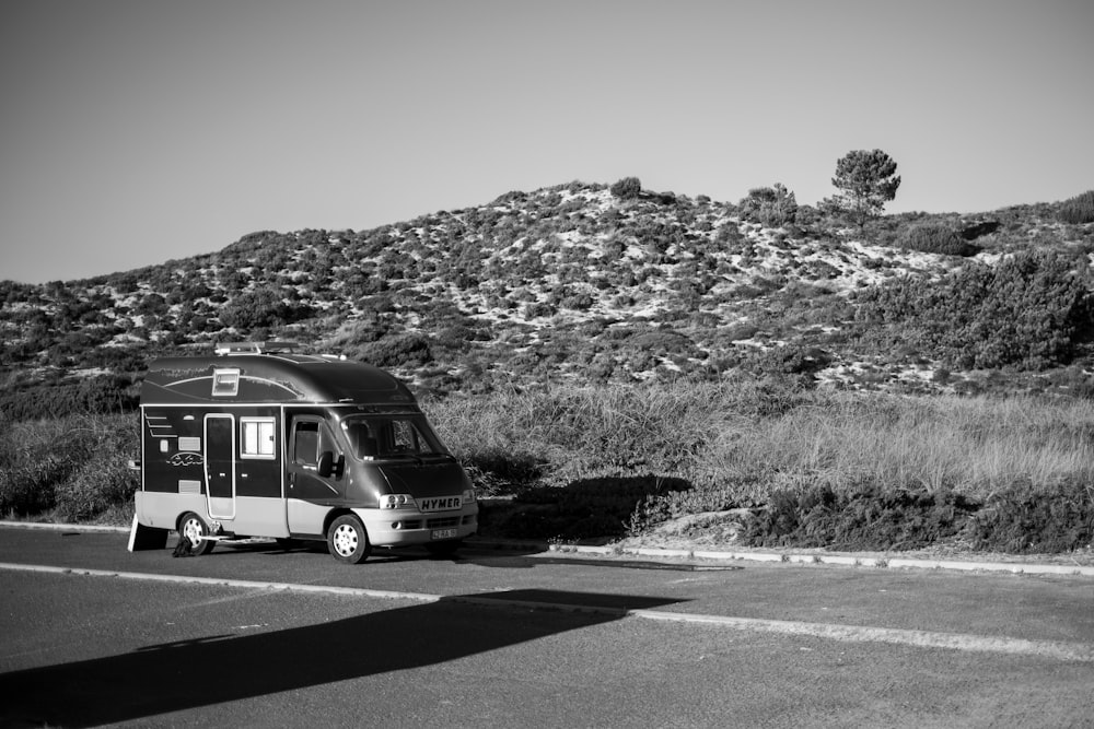 a black and white photo of a bus parked on the side of the road