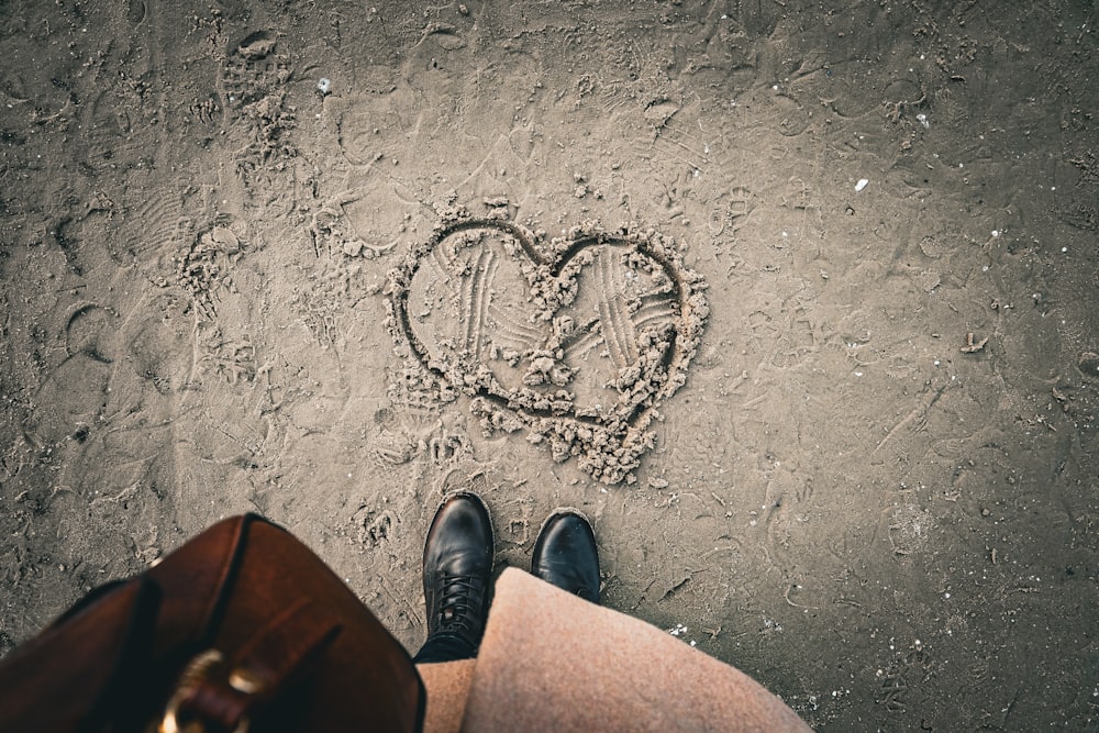 a person standing in the sand with a heart drawn in the sand