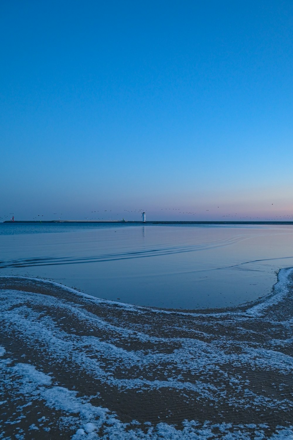 a large body of water sitting under a blue sky