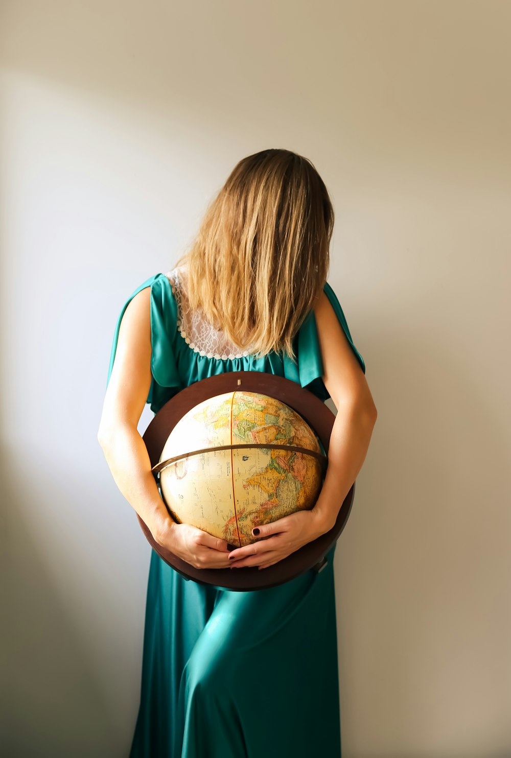 a woman in a green dress holding a globe