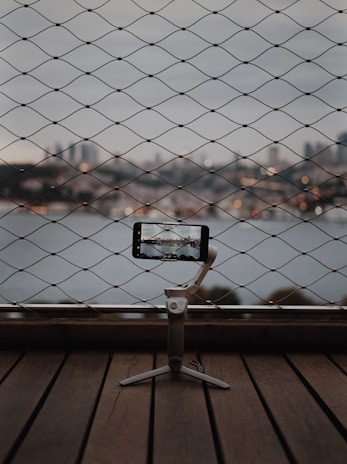 A travel content creator filming with a smartphone mounted on a compact tripod, set against an urban backdrop.