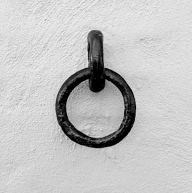 A chic black metal applique mounted on a white cassé wall, complementing natural wood accents.