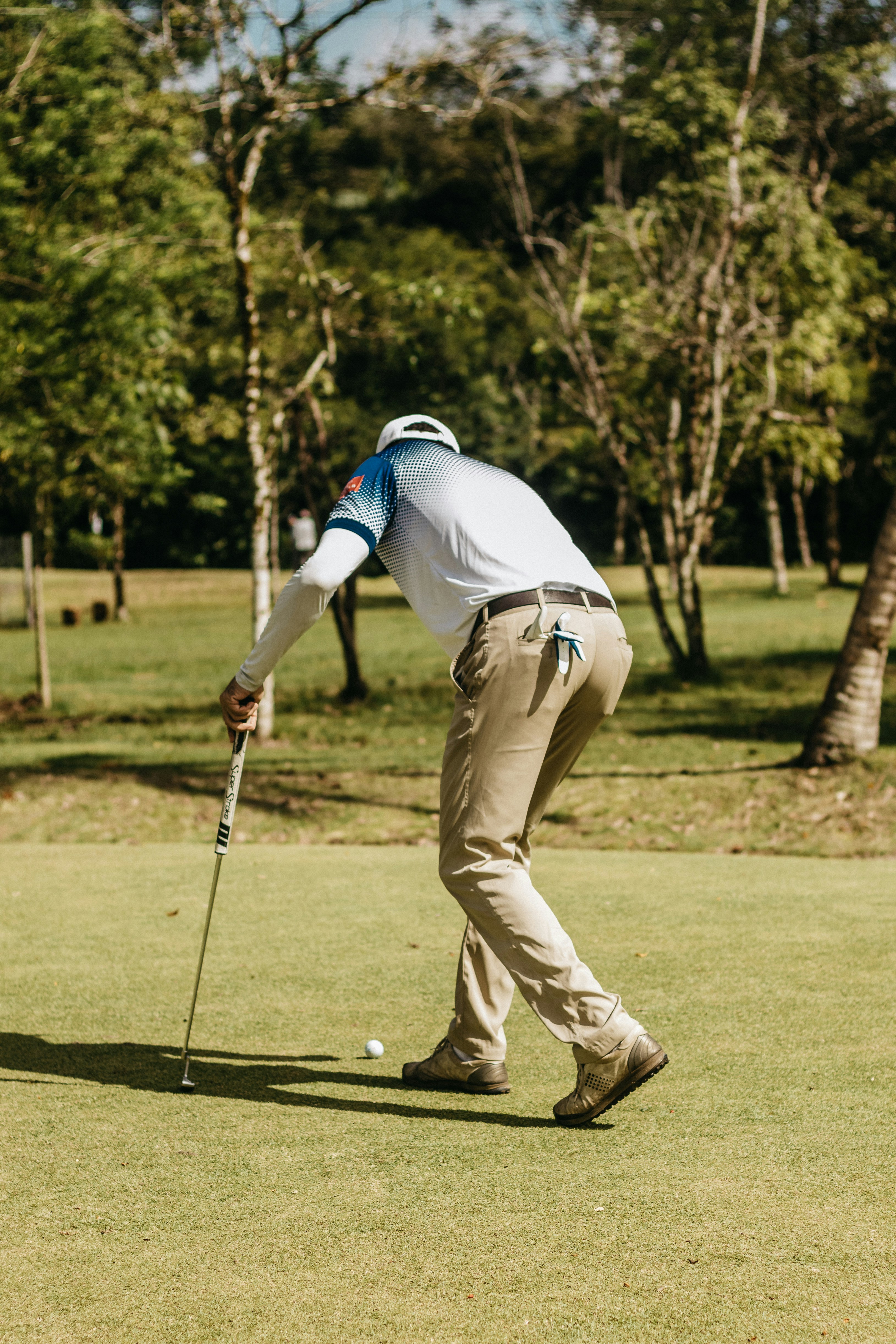 a man in white shirt and khaki pants playing golf