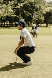 a man kneeling down on top of a green field