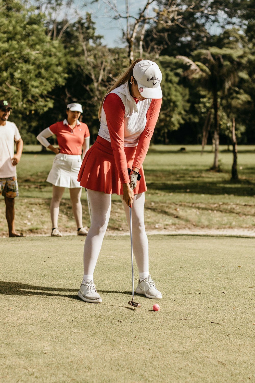 a woman in a red dress is playing golf