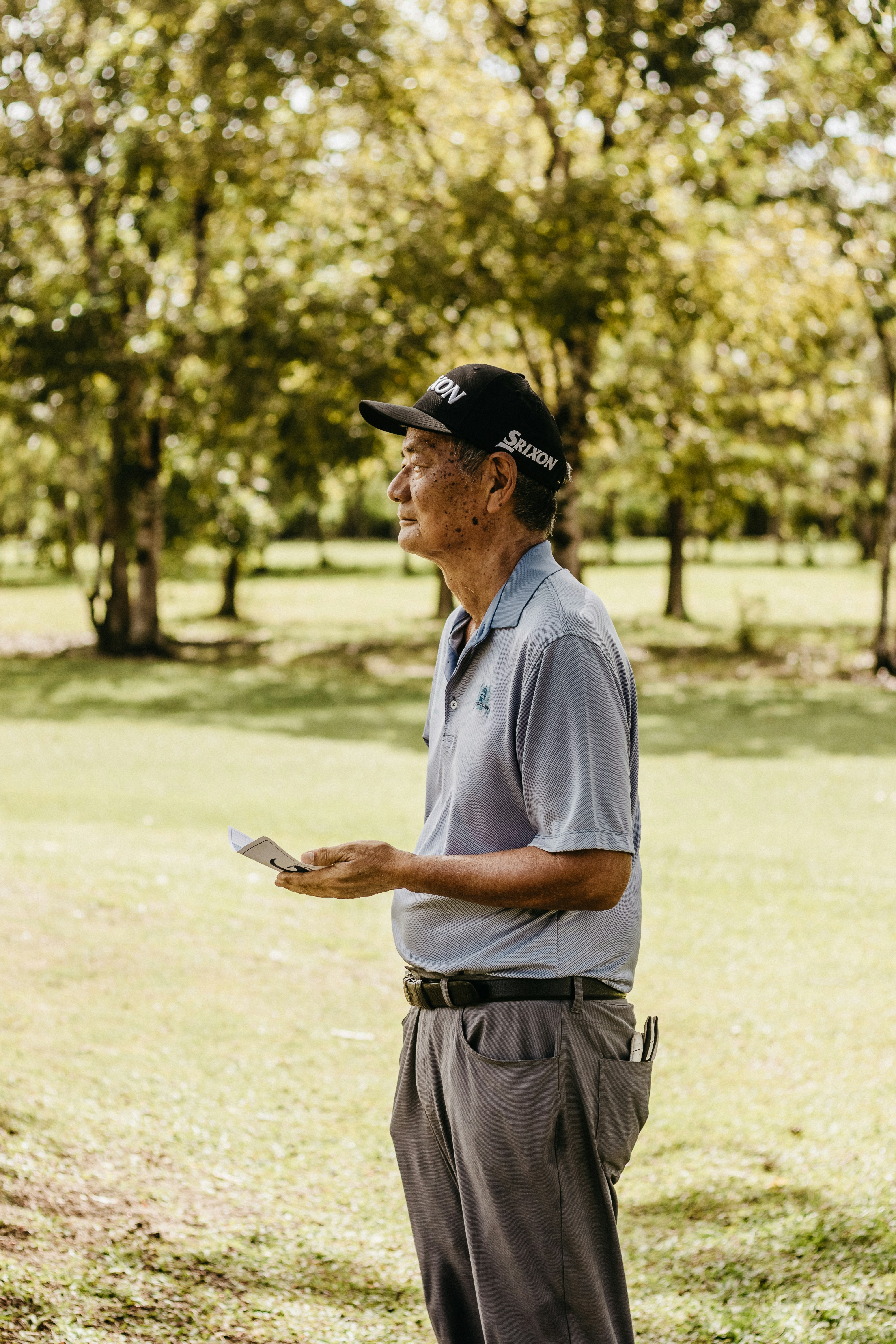 a man standing in a park holding a piece of paper