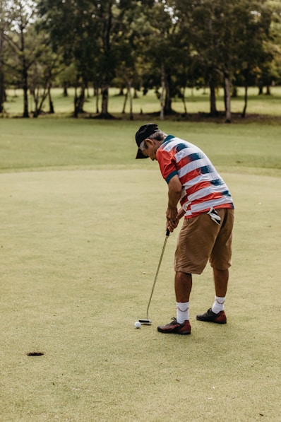 a man in a red, white and blue shirt is playing golf