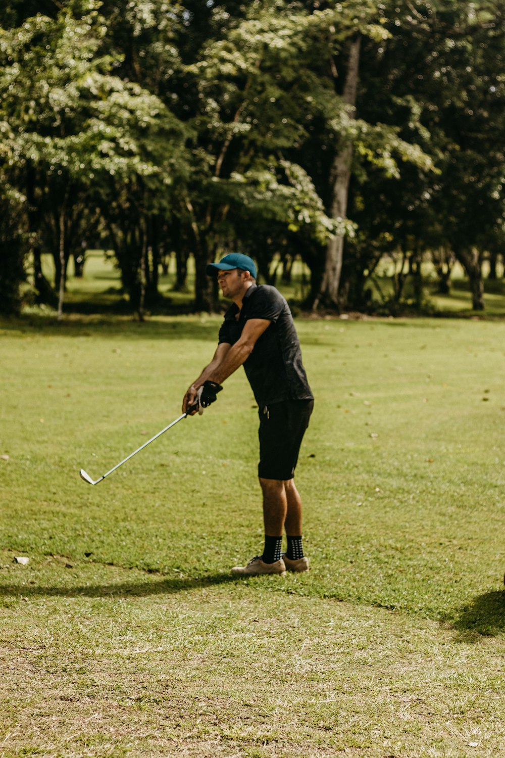 a man holding a golf club on a lush green field