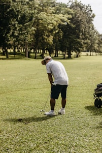 A close-up of a golfer's hands gripping a club on a lush green course under a clear blue sky.