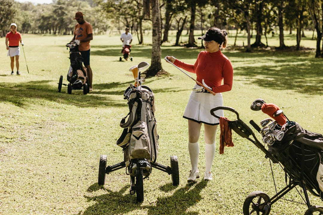 a woman in a red shirt and white skirt playing golf,