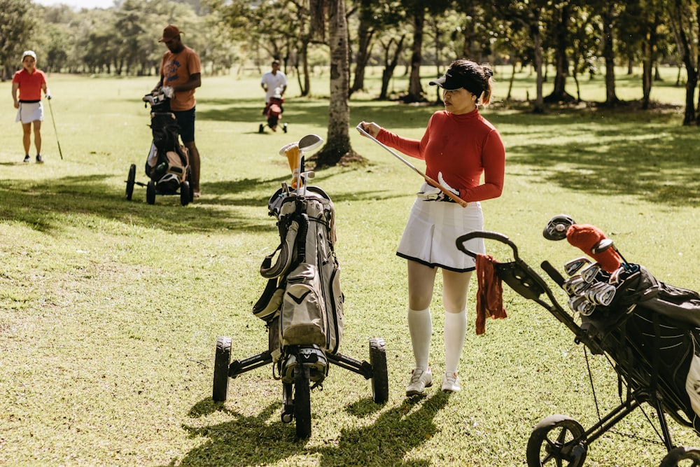 a woman in a red shirt and white skirt playing golf