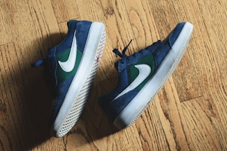 A pair of colorful kids' sneakers on a light wooden floor, showing breathable mesh and sturdy soles.