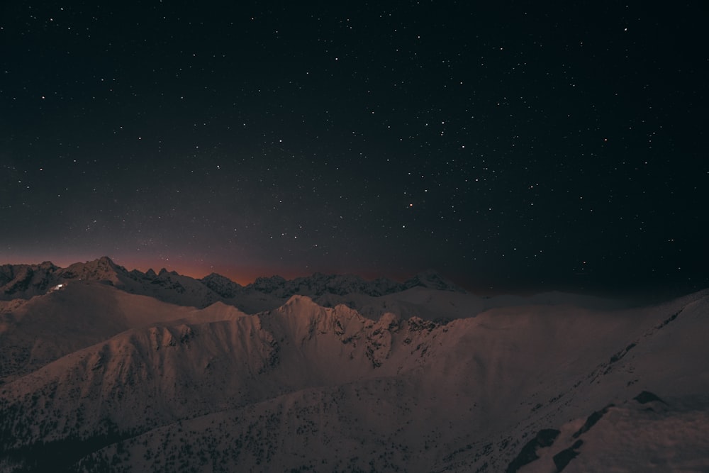 the night sky over a snowy mountain range