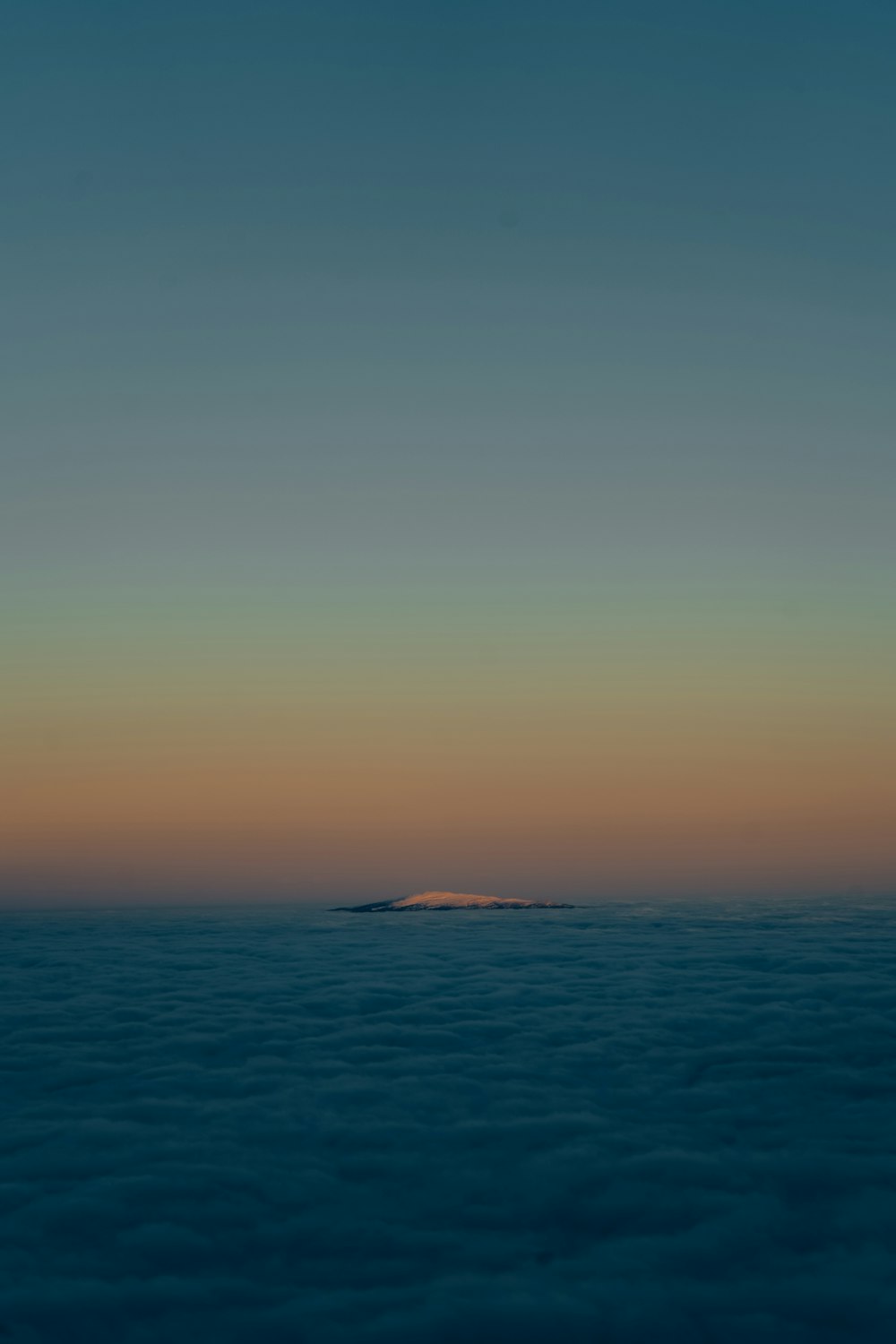a small island in the middle of a sea of clouds