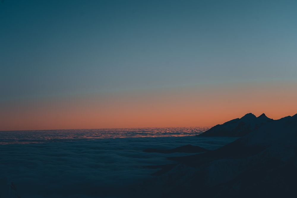 the sun is setting over the clouds and mountains