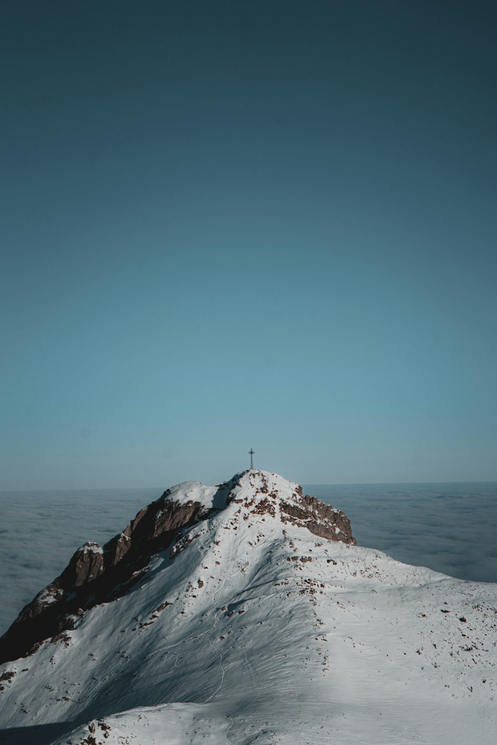 a snow covered mountain with a cross on top of it