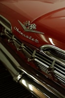 A vibrant red shirt featuring a custom vintage car print with shiny chrome accents.