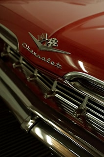 Close-up of shiny chrome detailing on a patriotic-themed hot rod at an outdoor event.