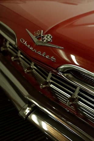 Close-up of shiny chrome detailing on a patriotic-themed hot rod at an outdoor event.