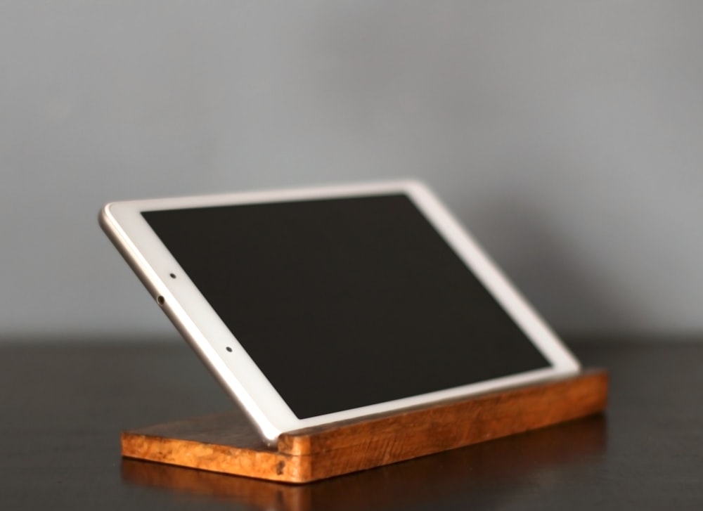 a tablet computer sitting on top of a wooden stand