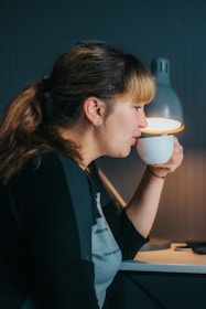 A person working on a laptop at a cozy home desk with a cup of tea nearby.