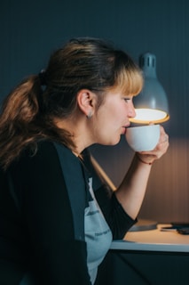 A young student sitting at a desk with a notebook and a cup of tea, looking thoughtful and calm in a cozy study space.
