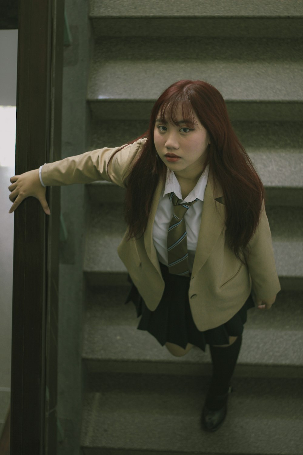 a woman in a suit and tie climbing up a flight of stairs