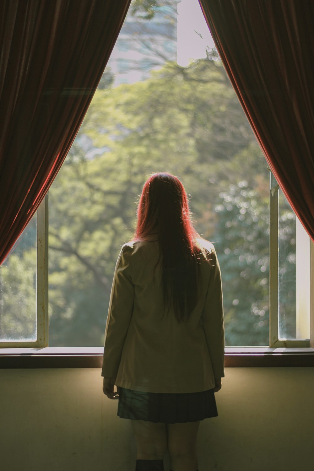 a woman standing in front of a window looking out