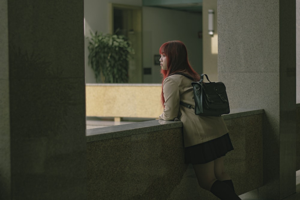 a woman with a backpack leaning against a wall