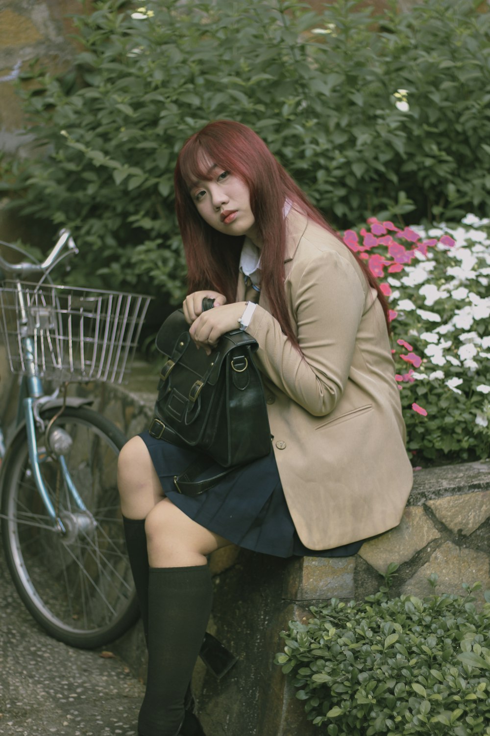 a woman sitting on a stone wall next to a bike