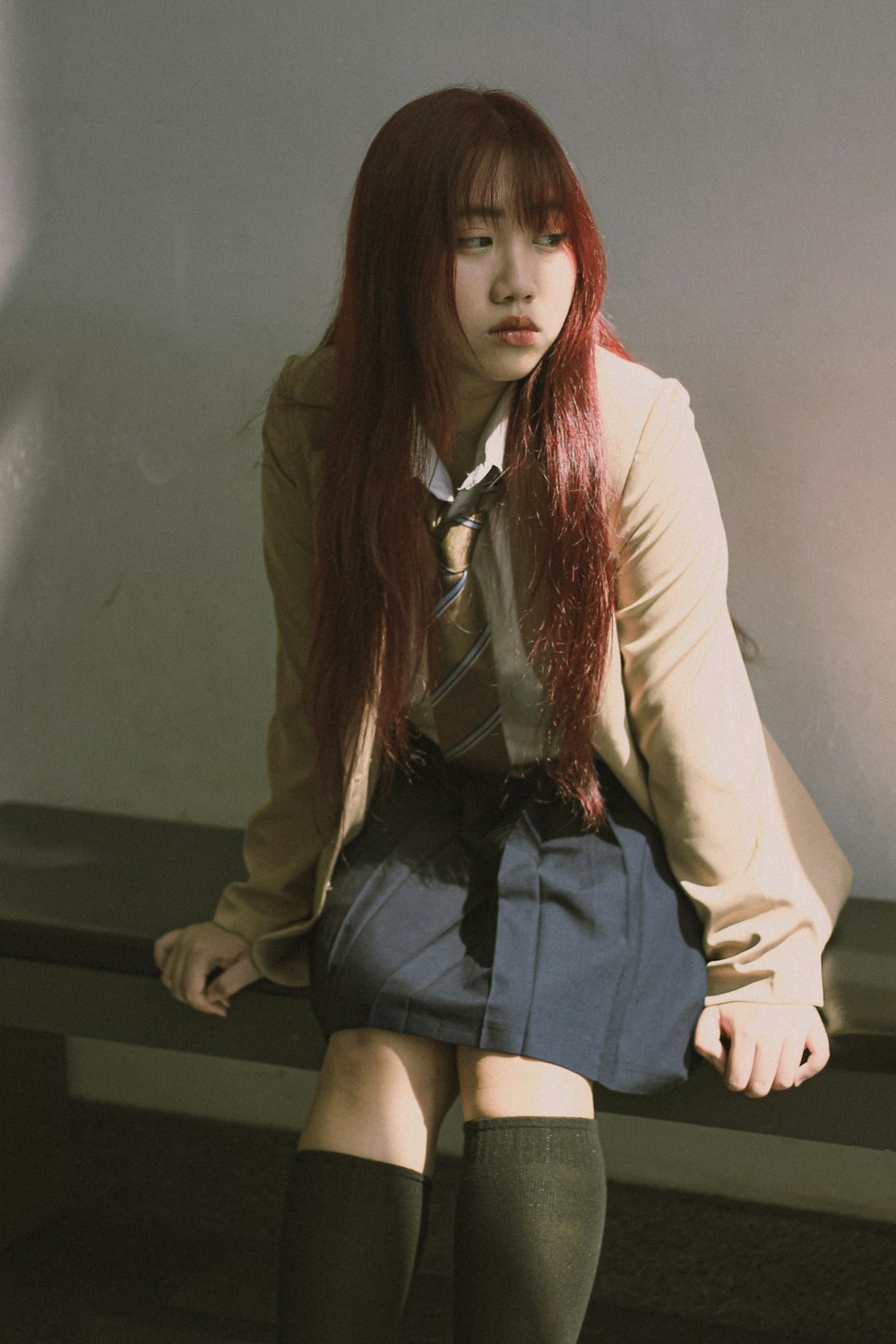 a woman with long red hair sitting on a bench