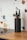 A black cylindrical knife holder containing several assorted knives is placed on a wooden kitchen countertop. The background features a terrazzo-style wall pattern with colorful fragments in shades of blue, orange, and black.