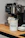 A smiling woman enjoying a fresh espresso next to her Rancilio coffee machine.