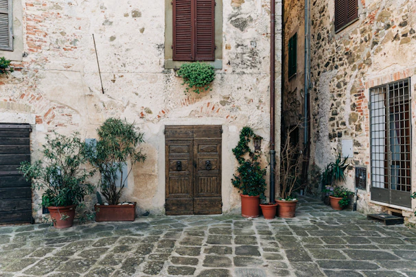 Sunlit courtyard of Torre Palazzone with antique stone walls and rustic wooden doors.