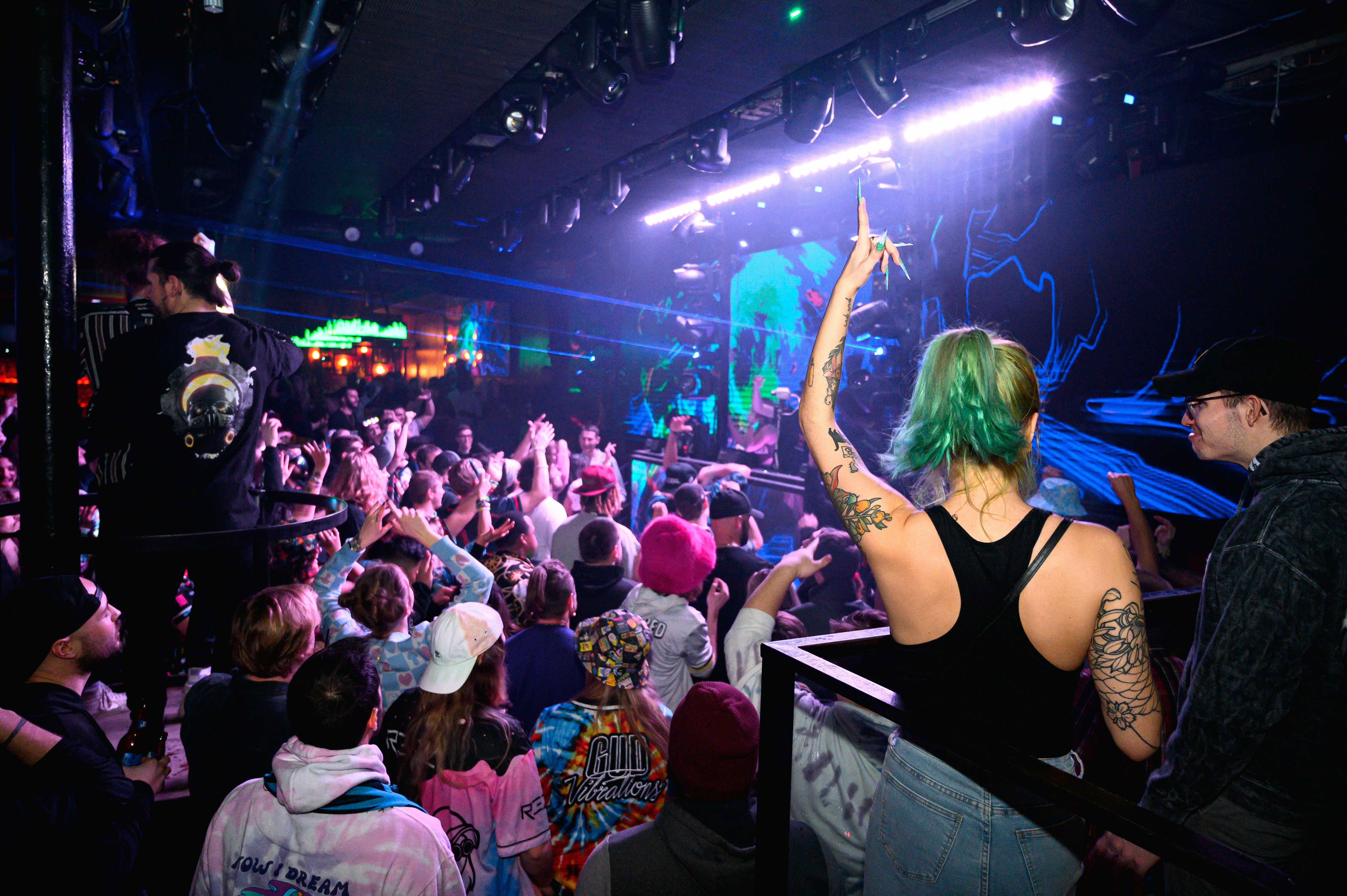 Crowd dancing at a concert with stage lights.