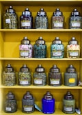 Colorful jars of homemade sauces and spices arranged on a light beige shelf.