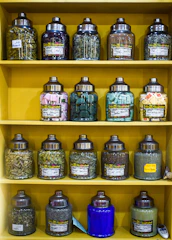 A collection of clear and frosted jars filled with colorful spices on a wooden kitchen shelf