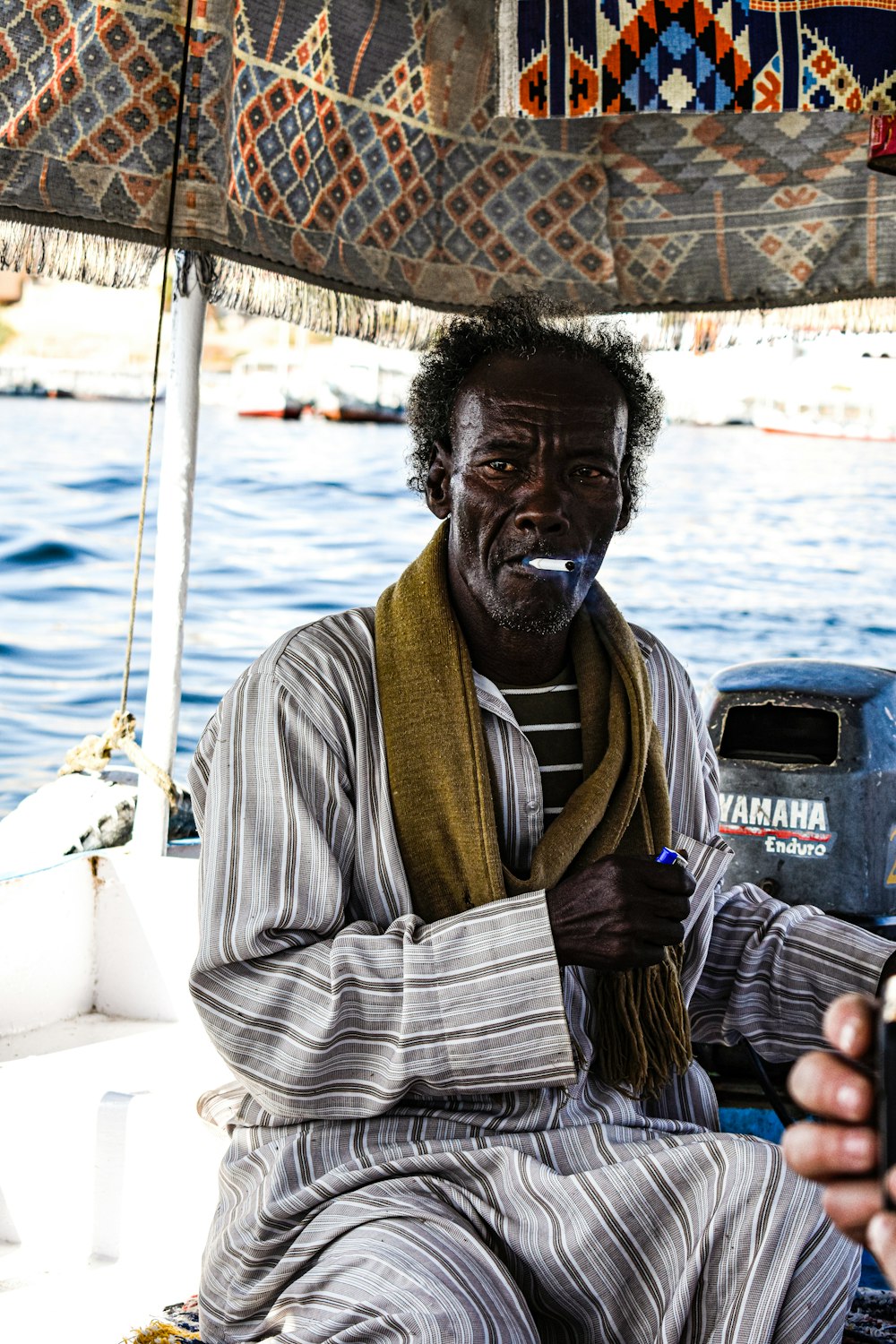 a man sitting on a boat smoking a cigarette