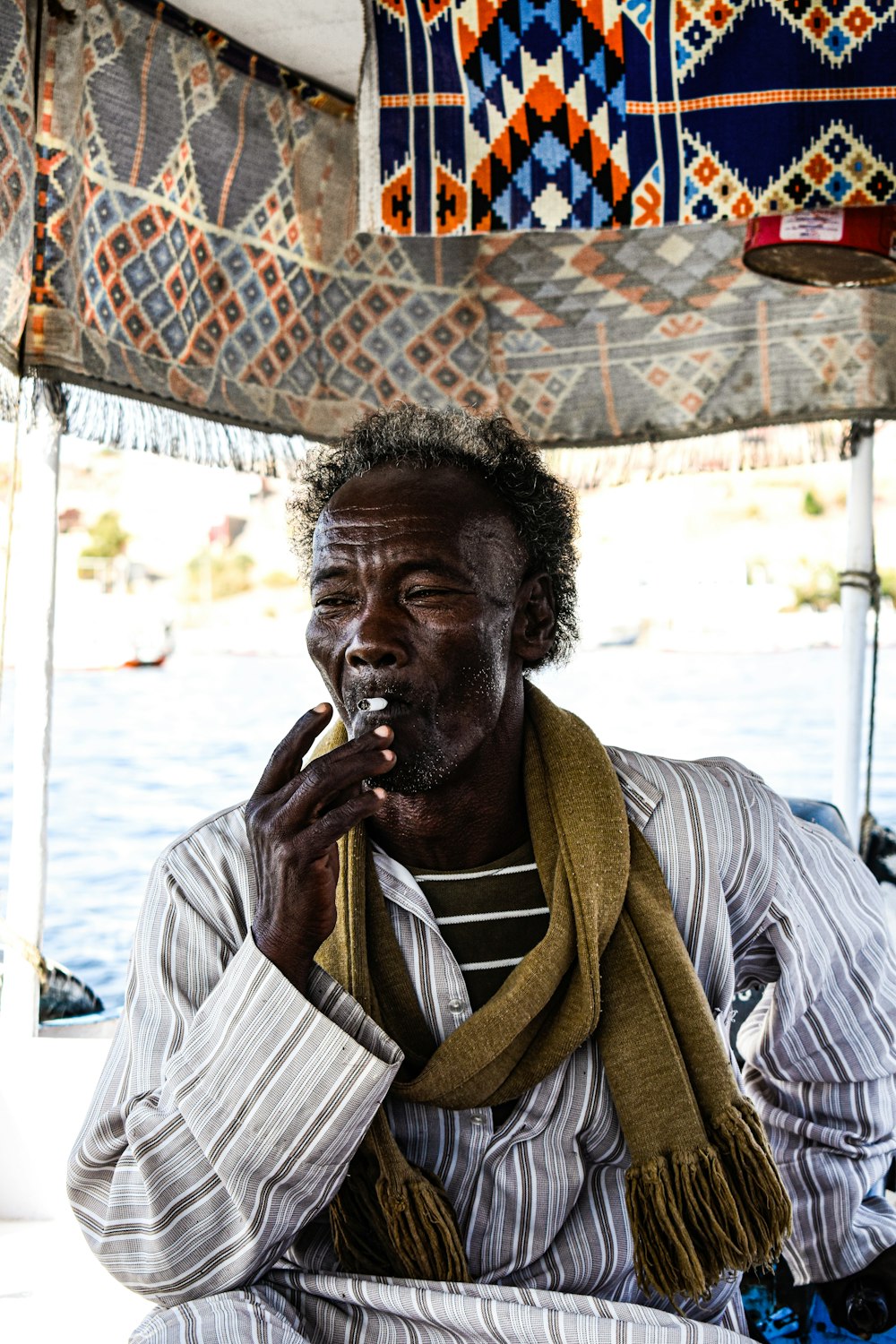 a man sitting on a boat smoking a cigarette
