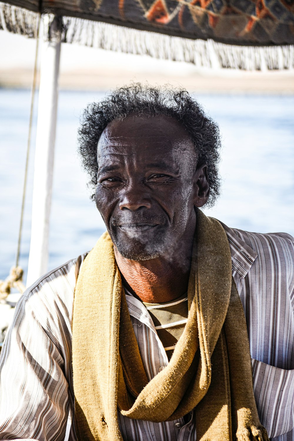 a man sitting on a boat with a scarf around his neck