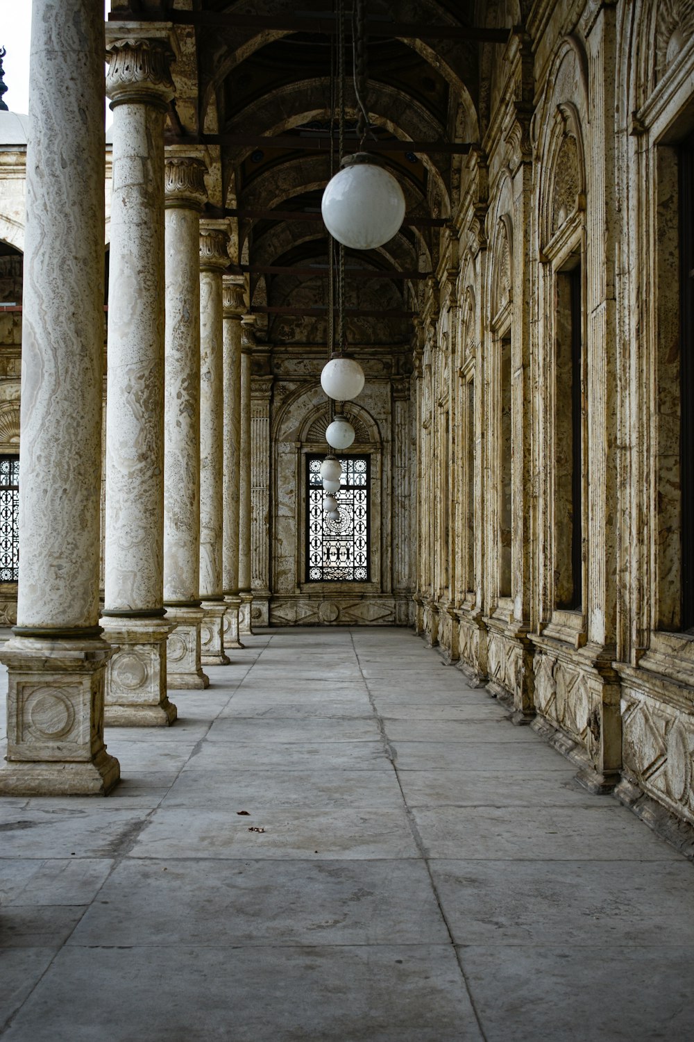 a long hallway with columns and a light hanging from the ceiling