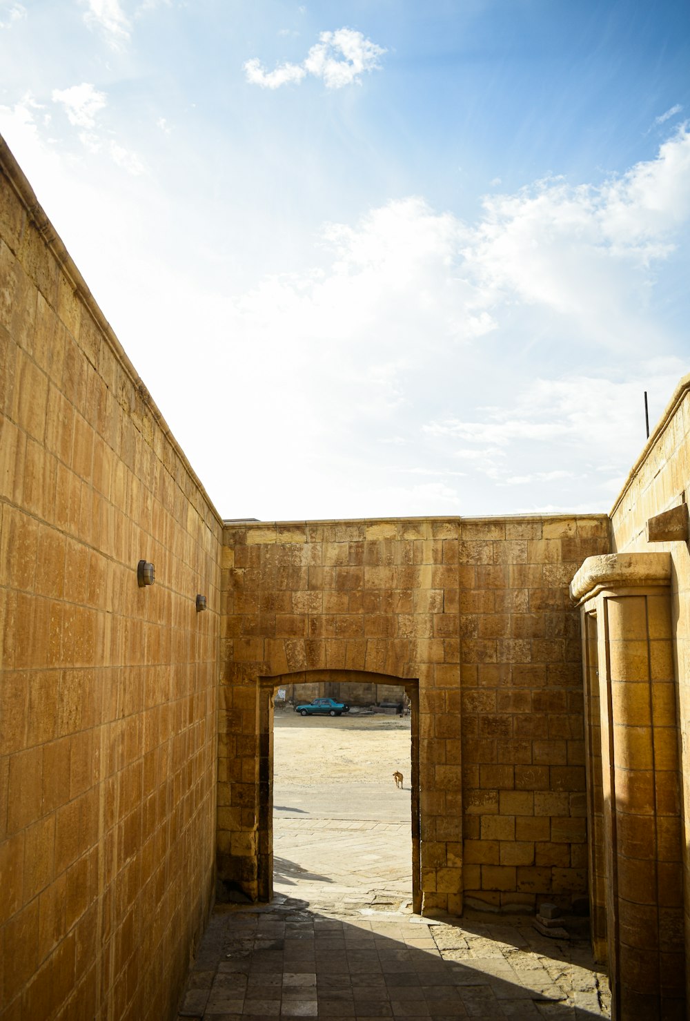 a brick wall with a doorway leading to a parking lot