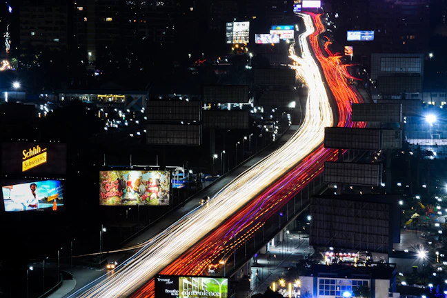A night-time shot of an illuminated outdoor flex ad glowing on a busy highway.